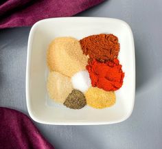 various spices in a white bowl on a purple cloth