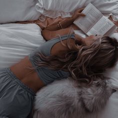 a woman laying in bed reading a book