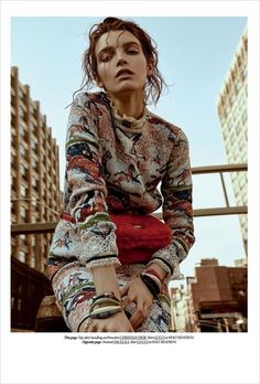 a woman sitting on top of a building next to tall buildings