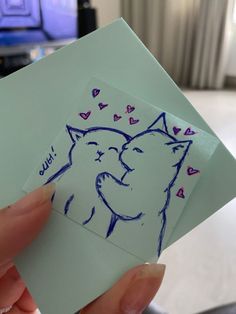 someone holding up a piece of paper with a drawing of a cat and hearts on it