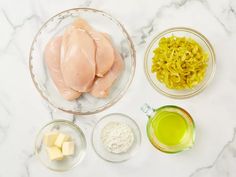 ingredients for chicken and noodles laid out on a white marble counter top, including eggs, cheese, butter, and oil