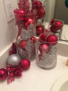 red and silver ornaments in glass vases on bathroom sink