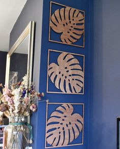 a blue wall with three wooden cutouts on it and some flowers in vases