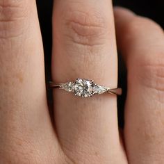 a woman's hand with a diamond ring on her left hand and the other hand holding an engagement ring