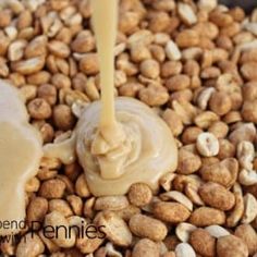 peanut butter being poured on top of peanuts