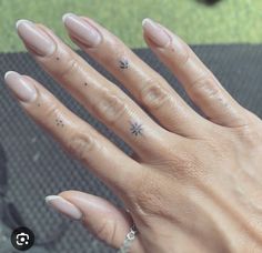 a woman's hand with some nail polish on her nails and a flower tattoo