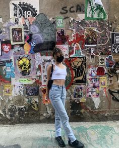 a woman standing in front of a wall covered with stickers