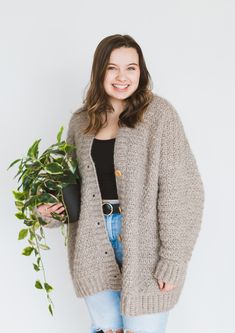 a smiling woman holding a potted plant and wearing a cardigan over her shoulders