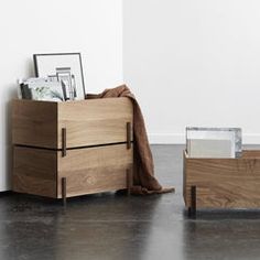 a wooden box sitting on top of a floor next to a table with magazines in it