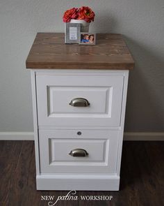 a white nightstand with two drawers and a photo on the top shelf next to it