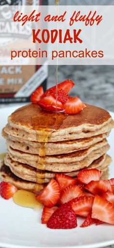 a stack of pancakes with syrup and strawberries on the plate next to it is text that reads light and fluffy kodiak protein pancakes