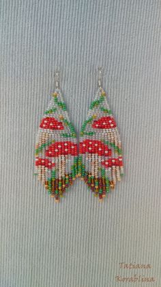 a pair of beaded earrings with red, green and white beads hanging from them