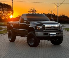 a black truck parked on top of a brick road