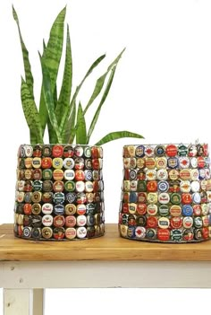 two planters made out of beer caps on a table with a potted plant in the background