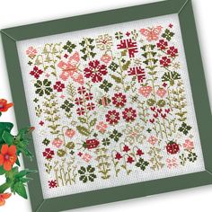 a cross stitch pattern with red flowers and green frame next to it's border