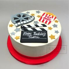 a birthday cake decorated with an image of a movie clapper, popcorn and stars