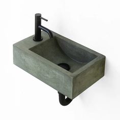 a concrete sink with black faucet and soap dispenser