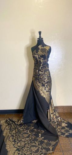 a mannequin is covered in black and gold fabric with an intricate design on it