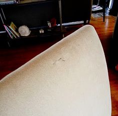 a white couch sitting on top of a hard wood floor next to a book shelf