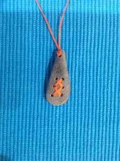 a rock with an x on it is hanging from a red string that has been placed in front of a blue background