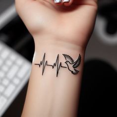 a woman's wrist tattoo with a bird and heartbeat