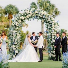 a bride and groom standing under an arch with flowers on it at the end of their wedding ceremony