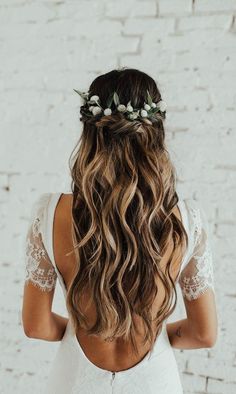 the back of a woman's head with long hair and flowers in her hair