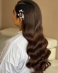 a woman with long brown hair wearing a white shirt and flower clip in her hair