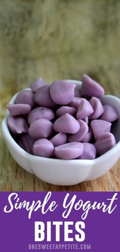 a white bowl filled with purple yogurt bites on top of a wooden table