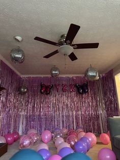 a party room with balloons, disco balls and ceiling fan in front of the wall