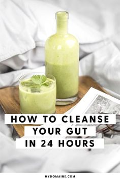 two glasses filled with green smoothie sitting on top of a wooden tray next to a bottle