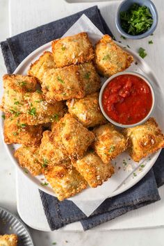 some fried food on a plate with ketchup and dipping sauce in a bowl