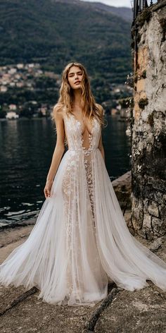 a woman in a wedding dress standing by the water