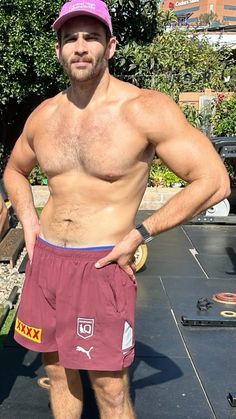 a shirtless man in shorts and a pink hat standing on top of a skateboard