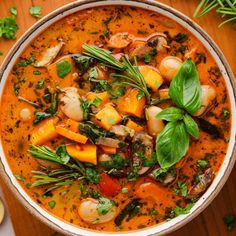 a bowl filled with soup and vegetables on top of a wooden table