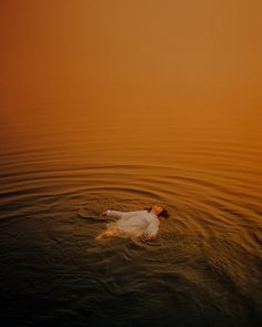 a person floating in the water at sunset