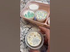 cupcakes with frosting and sprinkles are in a plastic container