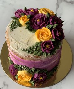 a multi layer cake decorated with flowers on a gold platter and marble counter top