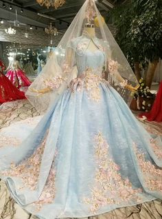 a blue wedding dress with pink flowers on the skirt and in the background is a mannequin wearing a veil