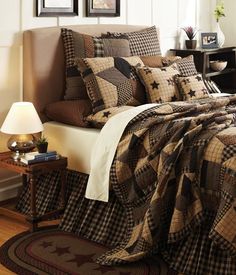 a bed with plaid comforter and pillows on top of it next to a night stand