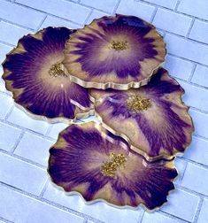 three purple flower shaped dishes sitting on top of a tile floor