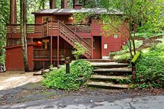 a red house in the woods with stairs leading up to it