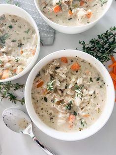 three bowls of chicken and dumpling soup on a white surface with carrots, parsley