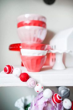 red and white bowls are sitting on a shelf next to other items in the background