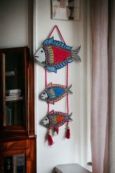 three wooden fish hanging on the wall next to a window