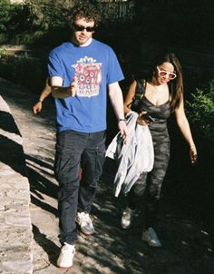 a young man and woman walking down a path holding onto each other's hands