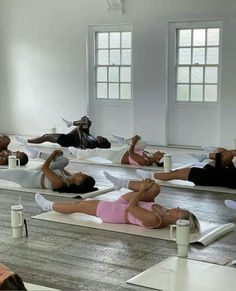 a group of people laying on their stomachs in a yoga class with mirrors behind them