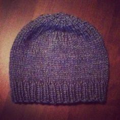 a purple knitted hat sitting on top of a wooden table