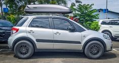 a small car parked in a parking lot with a kayak on top of it's roof