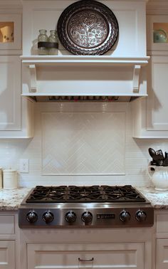 a stove top oven sitting inside of a kitchen next to white cabinets and counter tops